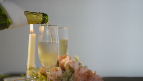 Close-Up-Of-Person-Pouring-Champagne-Into-Glass-At-Table-Set-For-Meal-In-Restaurant-1